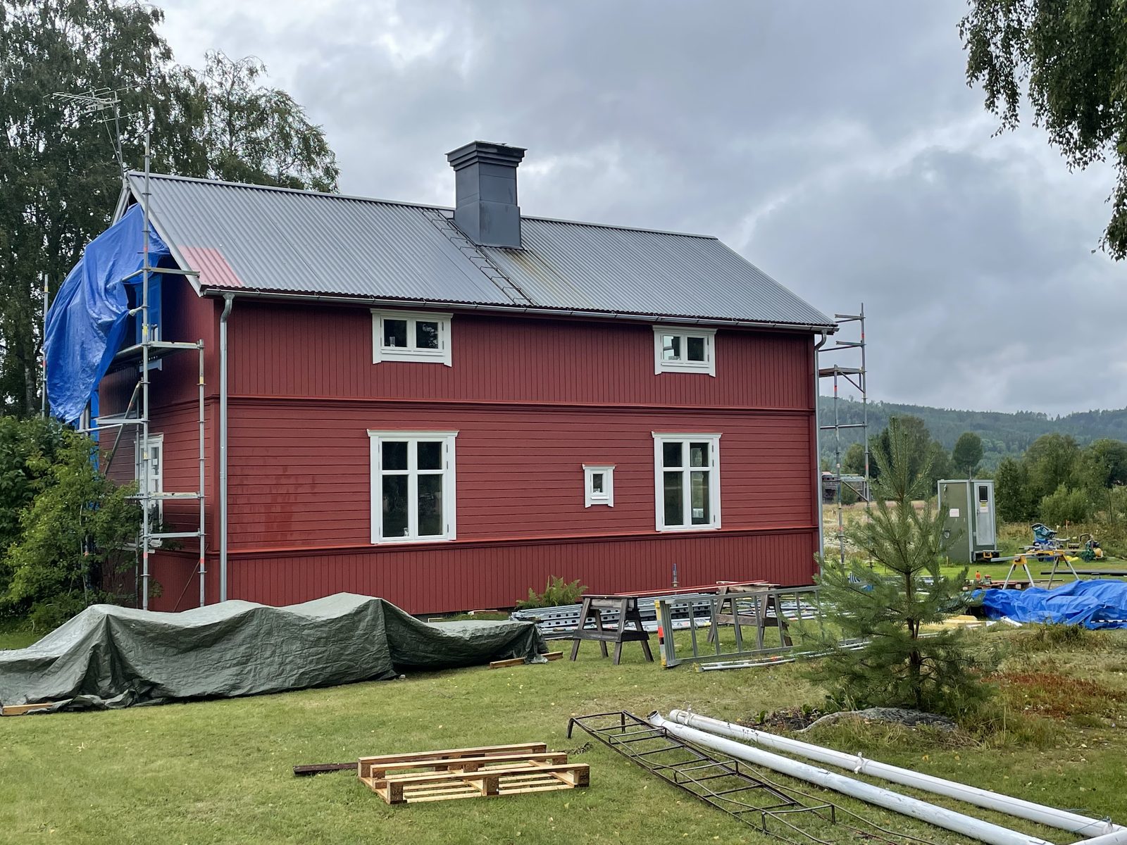 Rött tvåvåningshus med ny stående panel och vita fönsterfoder, Lucksta