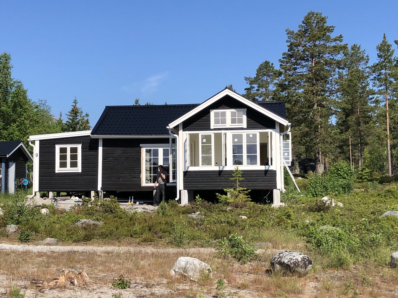 Fritidshus som står på betongplintar bland ljung och sten
