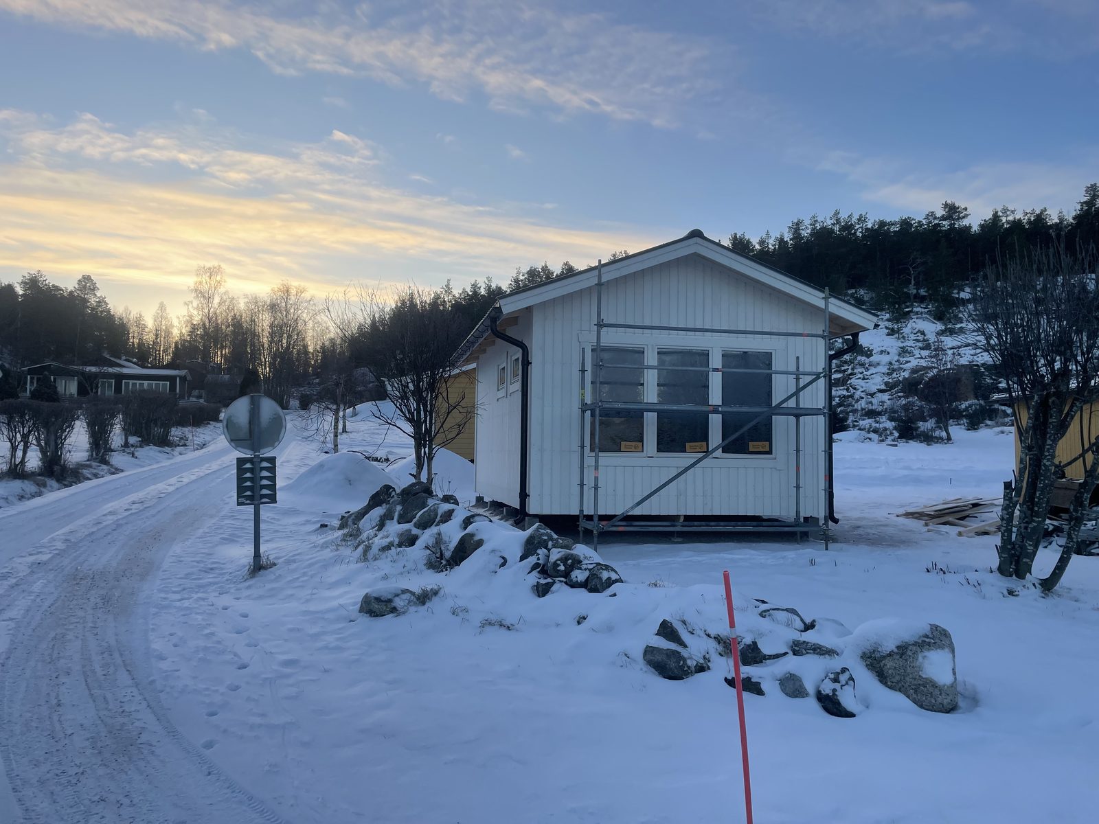 Vitt småhus med stora fönster och byggställning i vinterlandskap, Njurunda